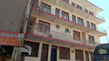Un edificio de varios pisos con balcones, un cartel y un automóvil estacionado.