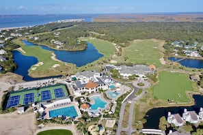 Eine Vogelperspektive auf einen Golfplatz mit mehreren Teichen, einem Schwimmbad, Tennisplätzen und Wohnhäusern.
