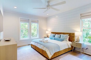 A bedroom with a bed, nightstands, a ceiling fan, and windows. - Brand New Coastal Retreat, 5BR Dog Friendly, Cape Fear Station, Near East Beach & Shoals Club (Bald Head Island)