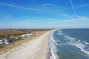 Ein Strand mit Häusern entlang der Küste, einem klaren Himmel und Meereswellen.
