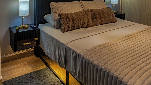 Un dormitorio moderno con una cama grande, aire acondicionado instalado en la pared y una lámpara de techo.