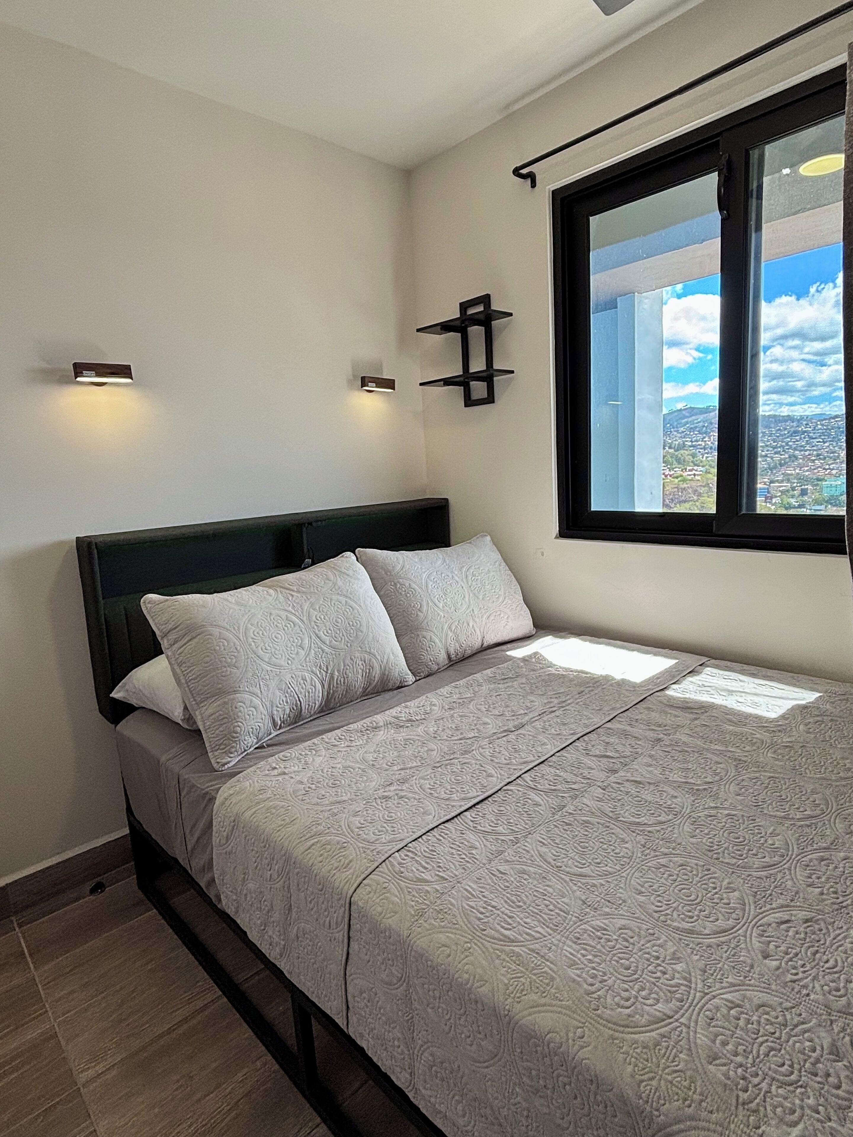 Une chambre à coucher avec un lit, une fenêtre et une vue sur le paysage urbain.