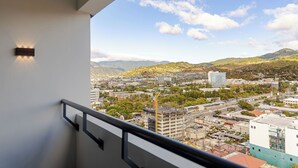 Un balcón con vista a la ciudad, incluyendo edificios y montañas.