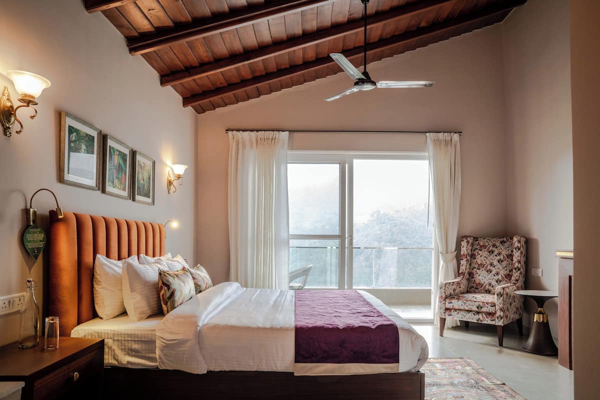 A bedroom with a bed, a chair, a window, and a ceiling fan.
