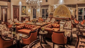 A spacious lounge with leather sofas, wooden tables, and a large chandelier. - amã Stays & Trails Aryananda Villas, Dhari (Dhari)