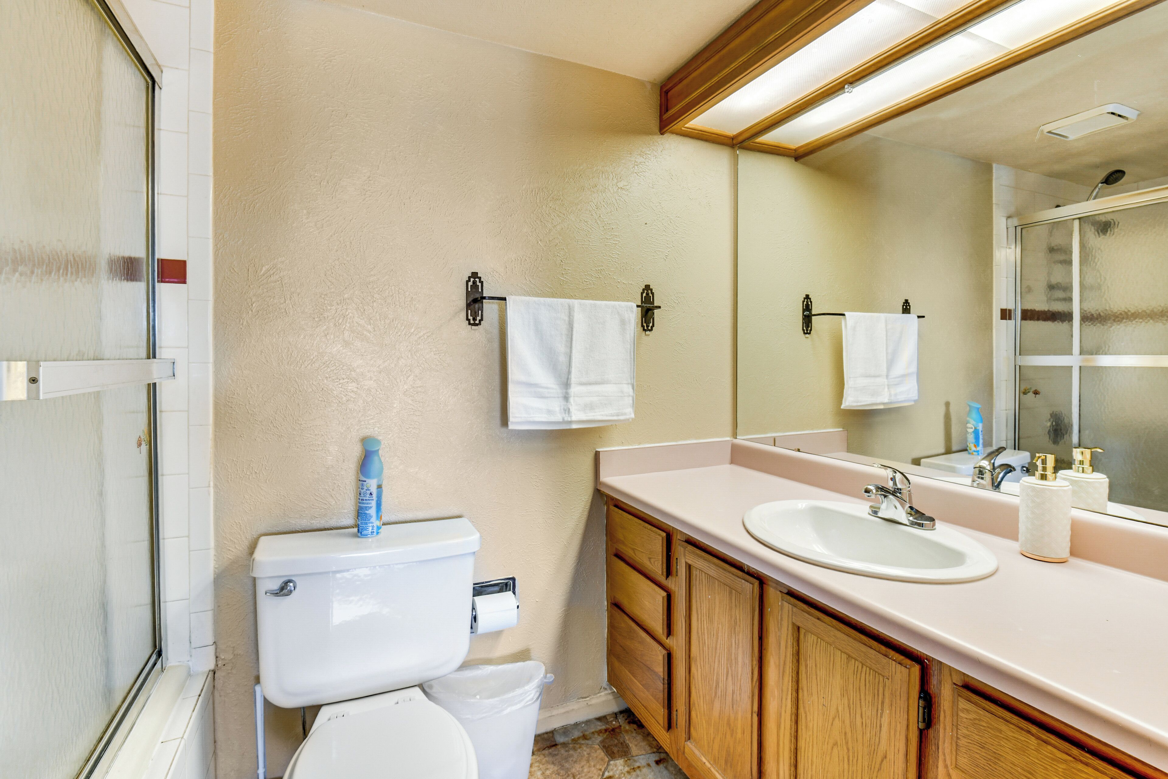 A bathroom with a toilet, sink, and mirror.