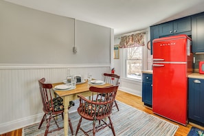 A dining area with a wooden table, two chairs, a red refrigerator, and blue cabinets. - Easy Beach Access! New London Apt w/ Kitchenette (New London)