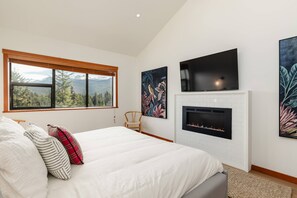 Un dormitorio con cama, chimenea, televisor y obras de arte en las paredes.