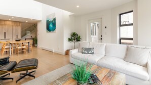 Ein modernes Wohnzimmer mit einer Couch, einem Couchtisch und einem Essbereich mit Holzmöbeln.