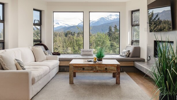 Ein modernes Wohnzimmer mit einer Couch, einem Couchtisch und großen Fenstern mit Blick auf die Berge.