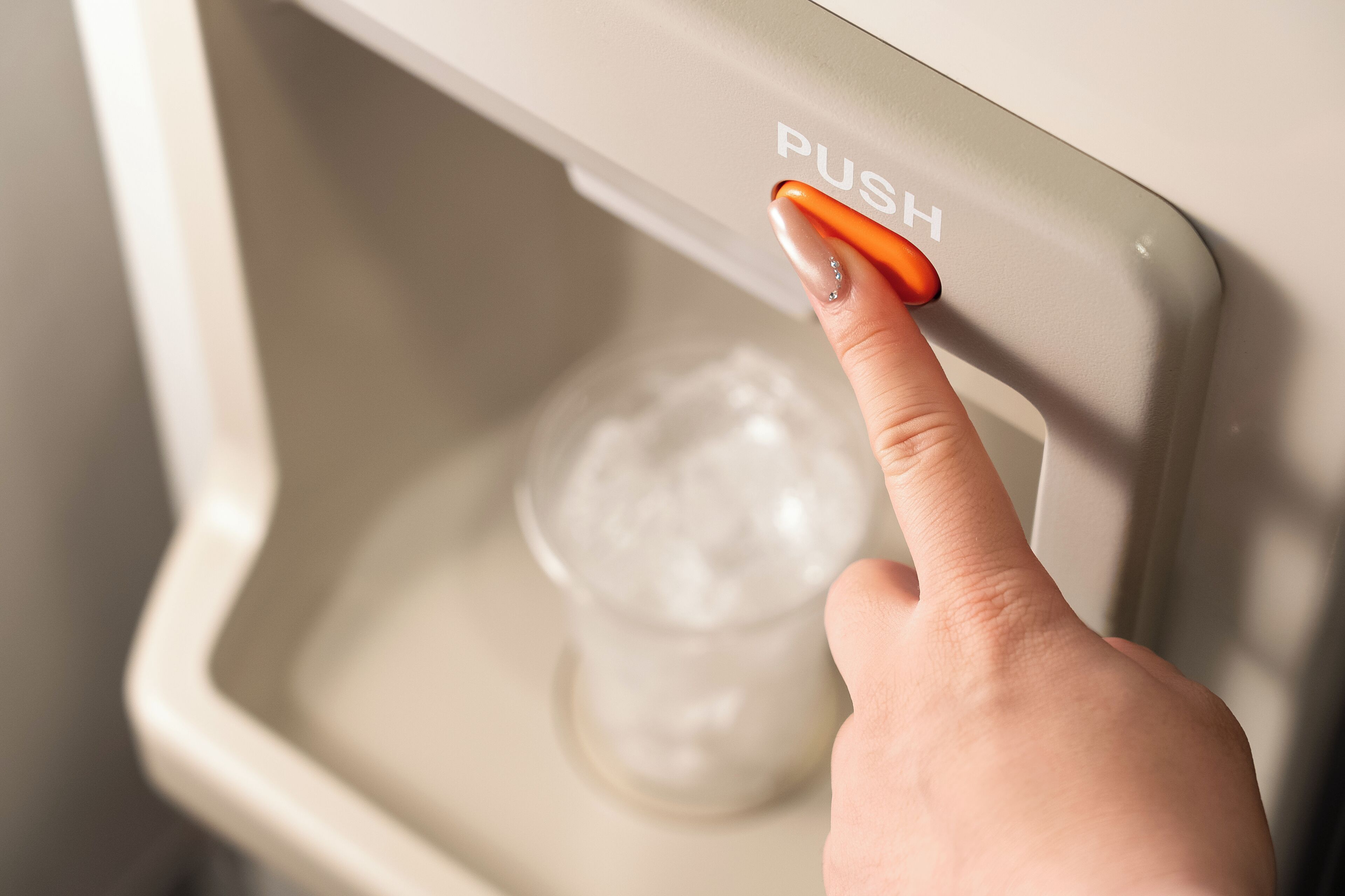 A hand pressing a button labeled 'PUSH' on a device.
