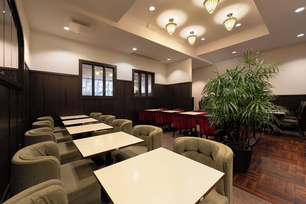 A conference room with tables and chairs, a large potted plant, and a wooden floor. - Hotel Oriental Express Ginza West (Tokyo)