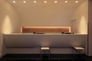 A modern reception area with a curved ceiling, recessed lighting, a reception desk, and two small tables.