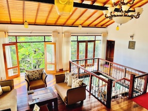 A spacious living area with a wooden ceiling, large windows, and a balcony with a railing. - The Grand Hanthana (Kandy)