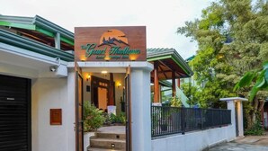 Das Außere des The Grand Hanthana Luxury Boutique Hotels mit einer auffälligen Beschilderung, einer überdachten Einfahrt und einer verschlossenen Auffahrt.