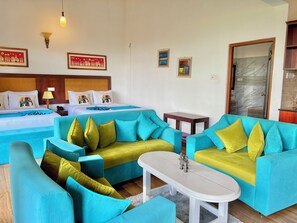 A hotel room with two beds, a sofa set, a small table, and artwork on the walls. - The Grand Hanthana (Kandy)