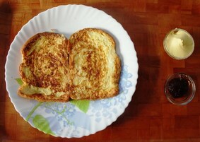 A plate with two grilled cheese sandwiches and a small bowl of jam.