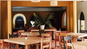 Ein Restaurant mit Holztischen und -stühlen, einem großen Topfpflanzen und einem modernen Innendesign.