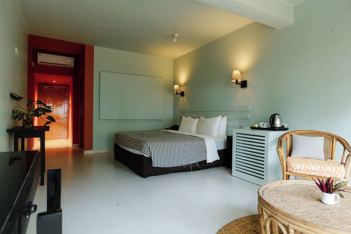 Une chambre à coucher comprenant un lit, une table de chevet, une chaise et un radiateur fixé au mur.