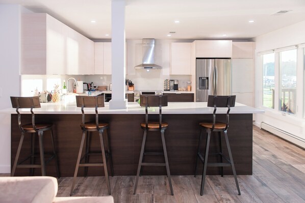 Une cuisine moderne dotée d’un îlot central, de tabourets de bar et d’une grande fenêtre.