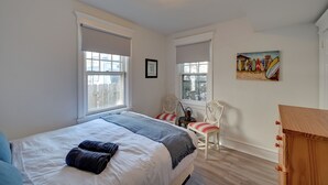 A bedroom with a bed, two chairs, a wooden dresser, and a painting on the wall. - 2 Blocks to Beach & Boardwalk: Ventnor City Escape (Ventnor City)
