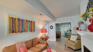 A living room with a brown sofa, a beige armchair, a fireplace, and a colorful abstract painting on the wall. - 2 Blocks to Beach & Boardwalk: Ventnor City Escape (Ventnor City)
