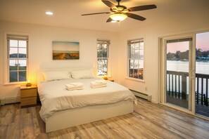 A bedroom with a large bed, a ceiling fan, and a view of a lake through a sliding door. - Game Room & Hot Tub: Family Gem on Lake Hopatcong (Lake Hopatcong)
