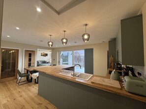A modern kitchen with a central island, built-in appliances, and pendant lighting. - Sunny Ridge is a modern, open-plan, sustainable bungalow, with stunning views. (Fort Augustus)