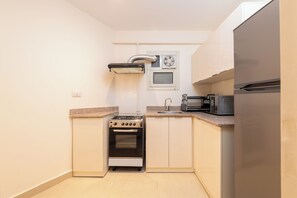 Eine kleine Küche mit Herd, Backofen, Mikrowelle und einem kleinen Fenster.