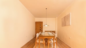 A dining area with a wooden table and chairs, a hanging light fixture, and a door in the background. - The Heart of Heliopolis 76 El Hegaz St (Cairo)