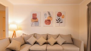 A living room with a beige sofa, a lamp, and three abstract paintings on the wall. - The Heart of Heliopolis 76 El Hegaz St (Cairo)