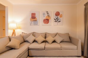 A living room with a beige sofa, a lamp, and three abstract paintings on the wall. - The Heart of Heliopolis 76 El Hegaz St (Cairo)