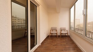A balcony with two chairs, a glass door, and a view of buildings. - The Heart of Heliopolis 76 El Hegaz St (Cairo)