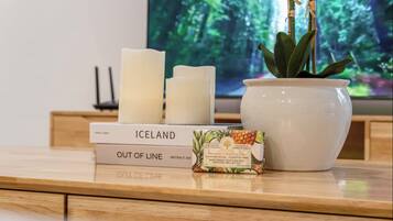 A wooden table with a white candle, a potted plant, a book titled "Iceland," and a small box of soap.