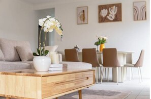 A modern living room with a wooden coffee table, a sofa, and a dining area with chairs and a table. - 4BR Warm & Relaxing Ripley Escape - Inspire Haven (Ripley)