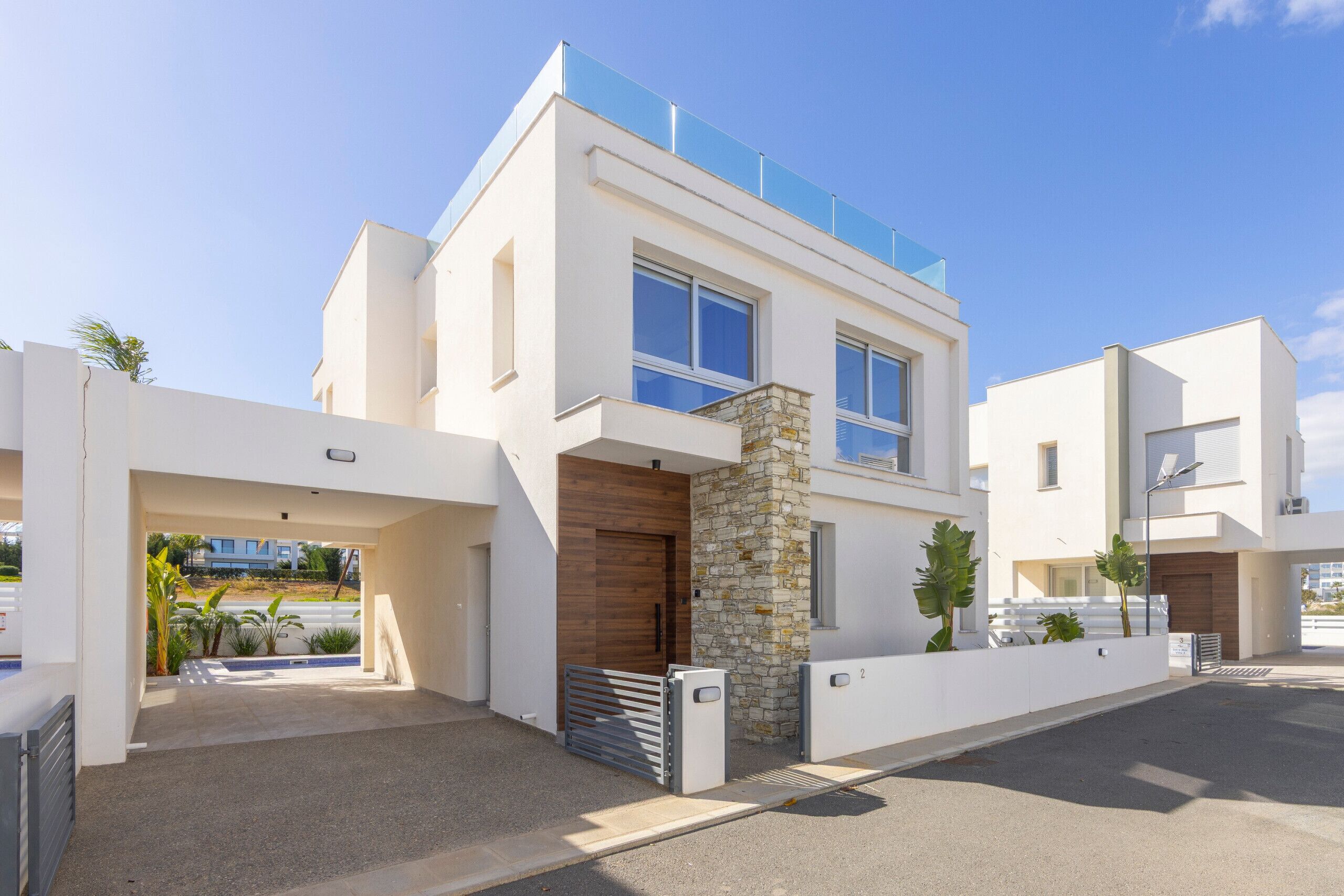 A modern two-story house with a stone facade, large windows, and a flat roof with solar panels.