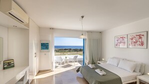 A modern bedroom with a bed, a desk, and a view of the beach. - Protaras Seafront Villa Galene Del Mar (Protaras)
