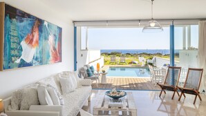 A modern living room with a white sofa, a coffee table, and a large abstract painting. - Protaras Seafront Villa Galene Del Mar (Protaras)