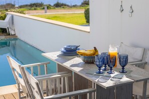 A poolside table with blue glassware, plates, and a fruit bowl. - Protaras Seafront Villa Galene Del Mar (Protaras)