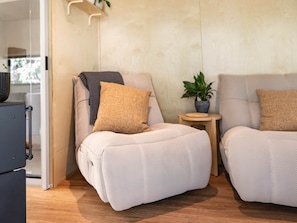 Une pièce moderne dotée de deux coins salon, d’une petite table d’appoint avec une plante et d’une cloison en verre.