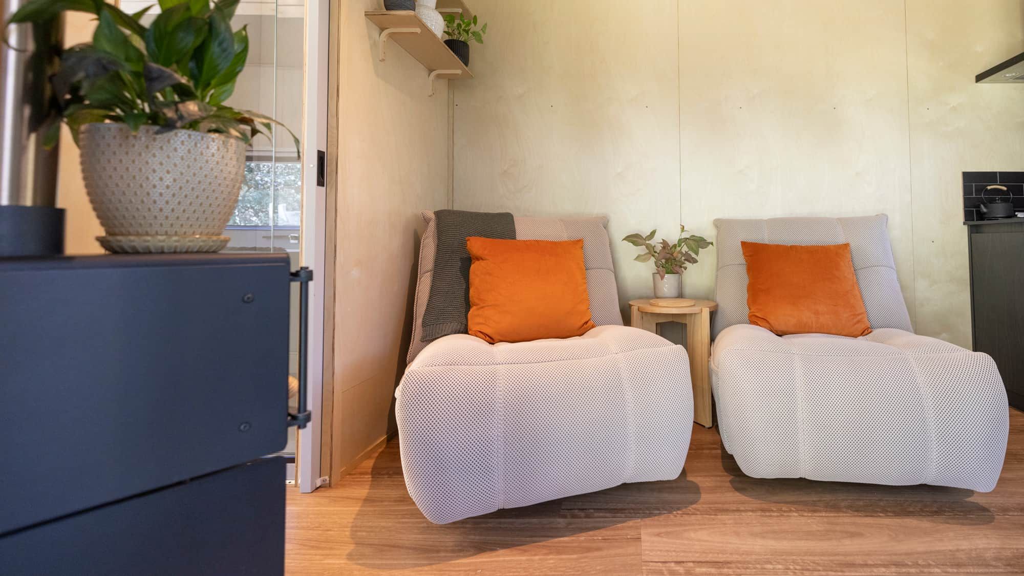 Ein modernes Wohnzimmer mit zwei Sesseln, einem kleinen Beistelltisch und einem Blumentopf.