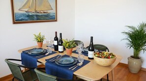 Une table à manger dressée pour quatre personnes, avec des bouteilles de vin, des verres et un saladier.