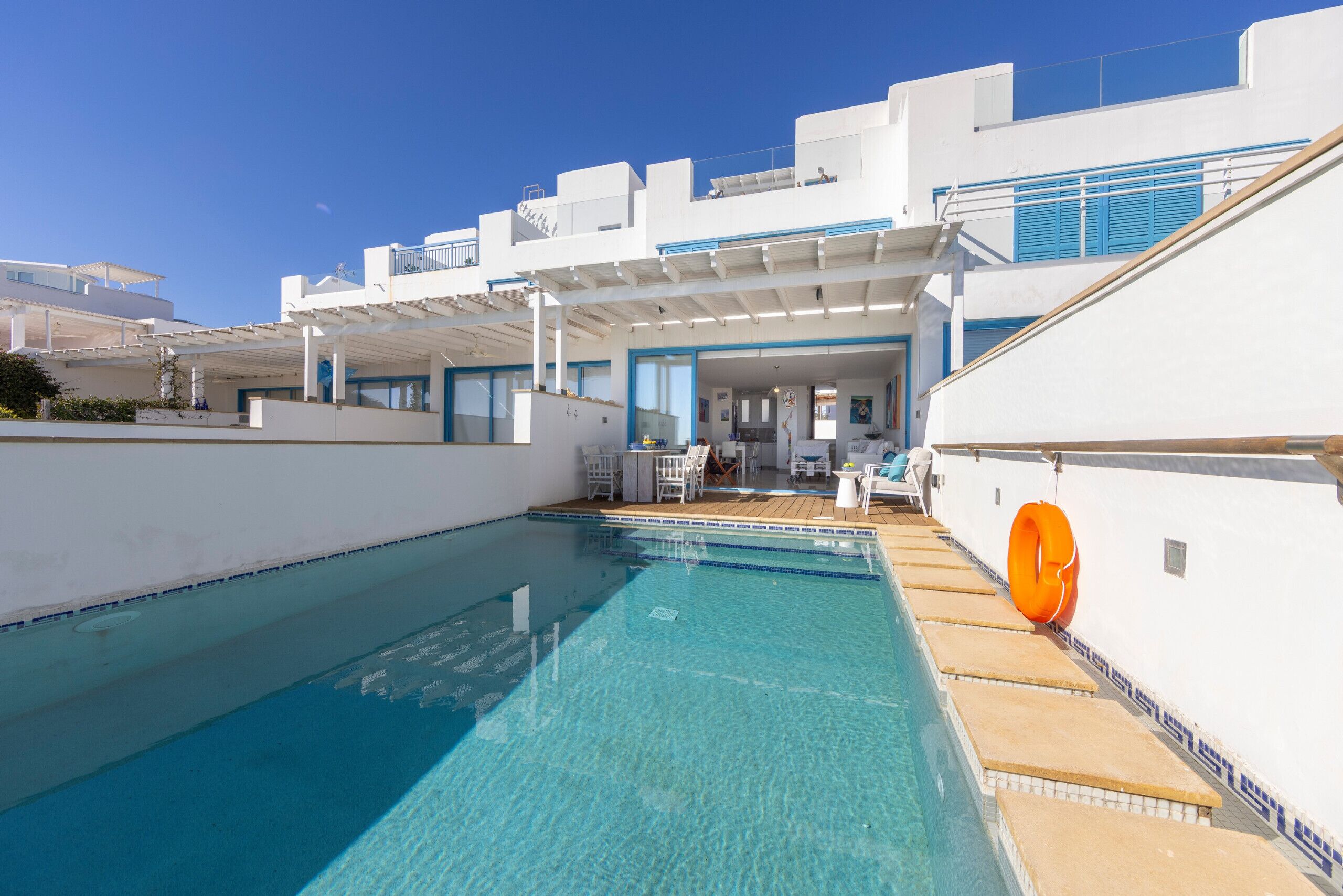 A modern pool area with clear blue water, white walls, and blue accents.