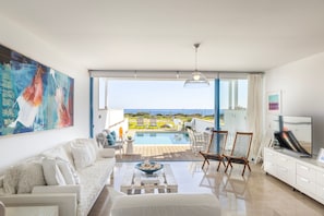 A modern living room with a pool, white furniture, and a large painting. - Protaras Seafront Villa Galene Del Mar (Paralimni)
