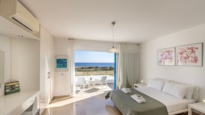 Ein modernes Schlafzimmer mit Bett, Schreibtisch und Blick auf den Strand.