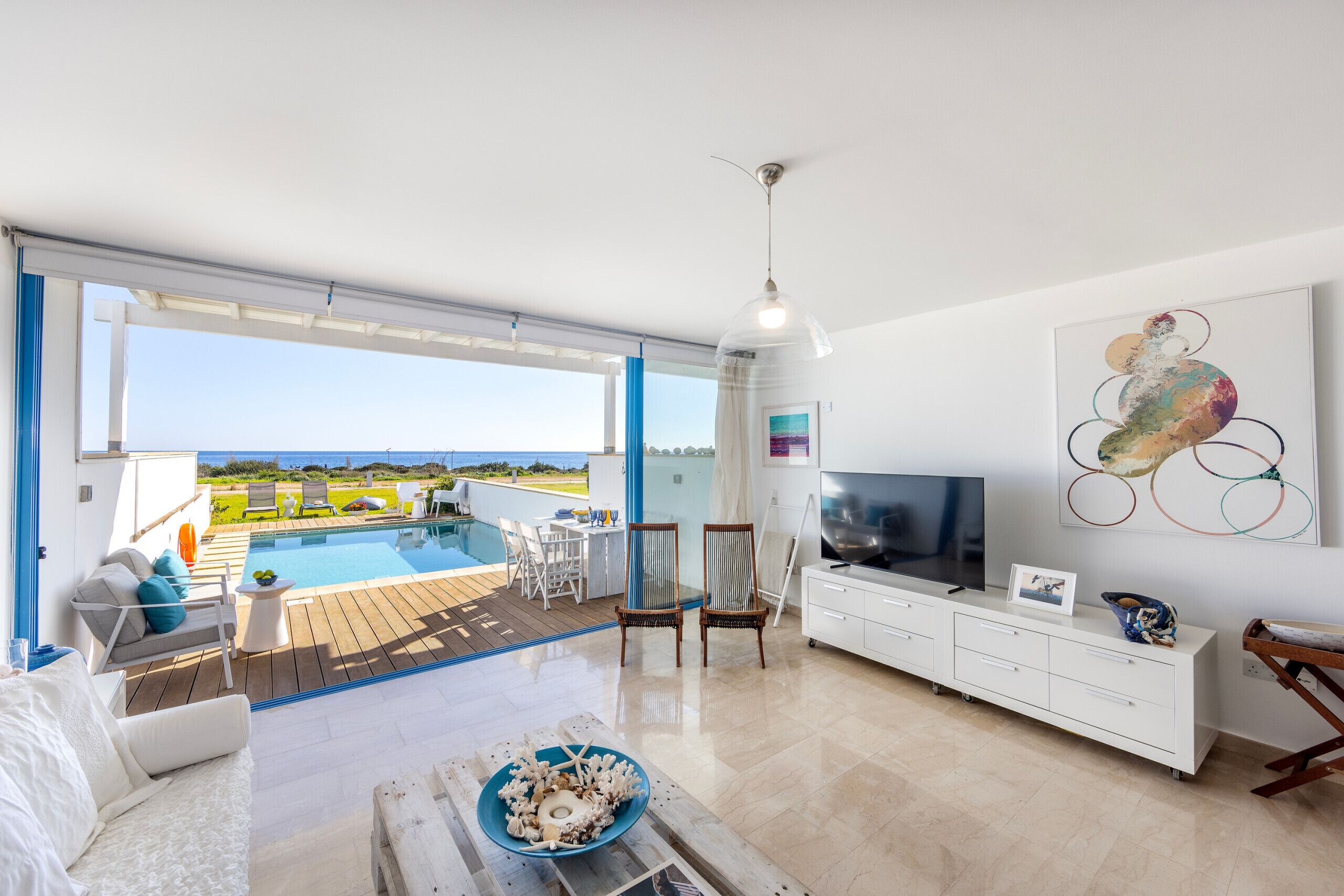 A modern living room with a pool view, a TV, and a dining area.