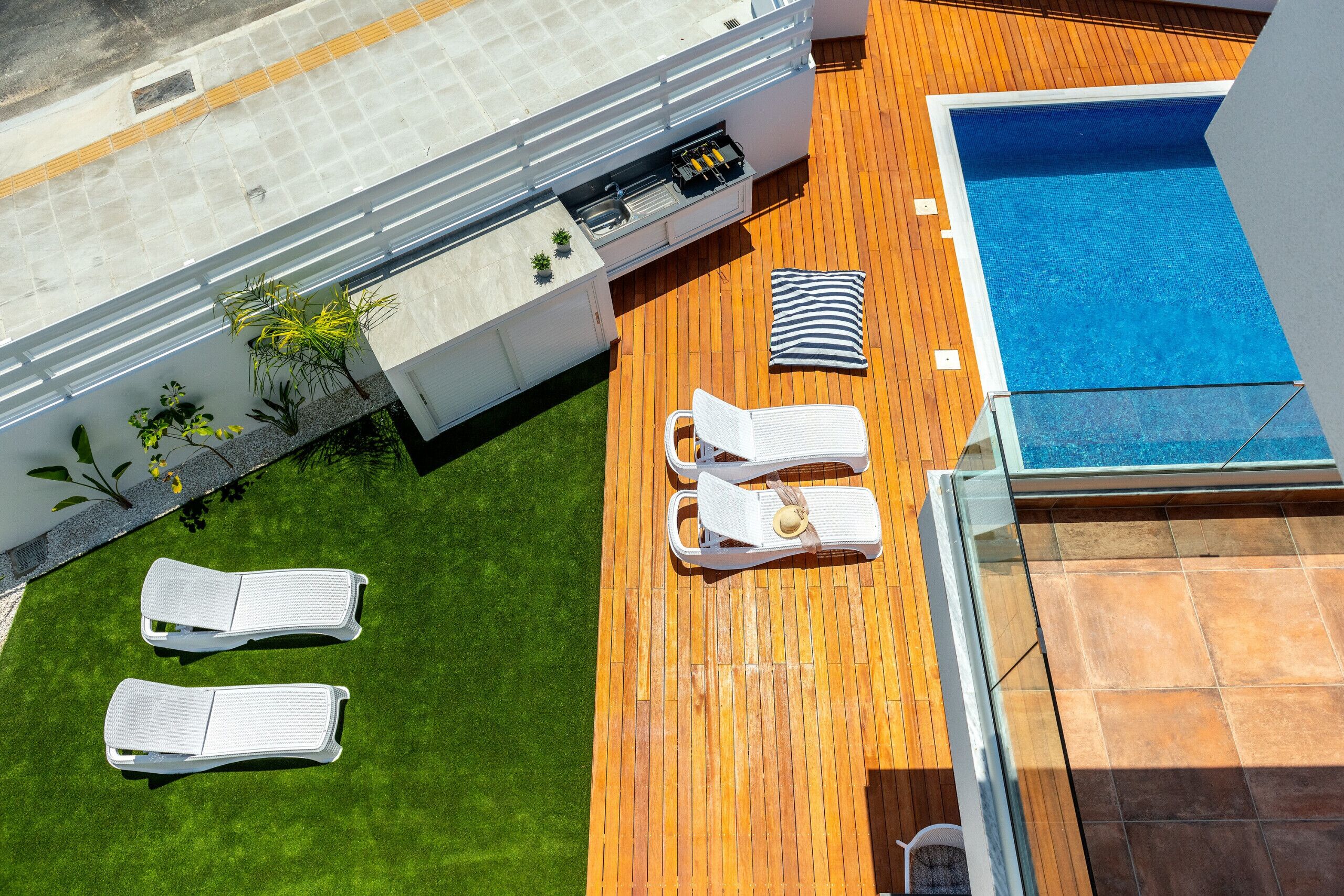 A rooftop pool area with two lounge chairs, a small pool, and a wooden deck.
