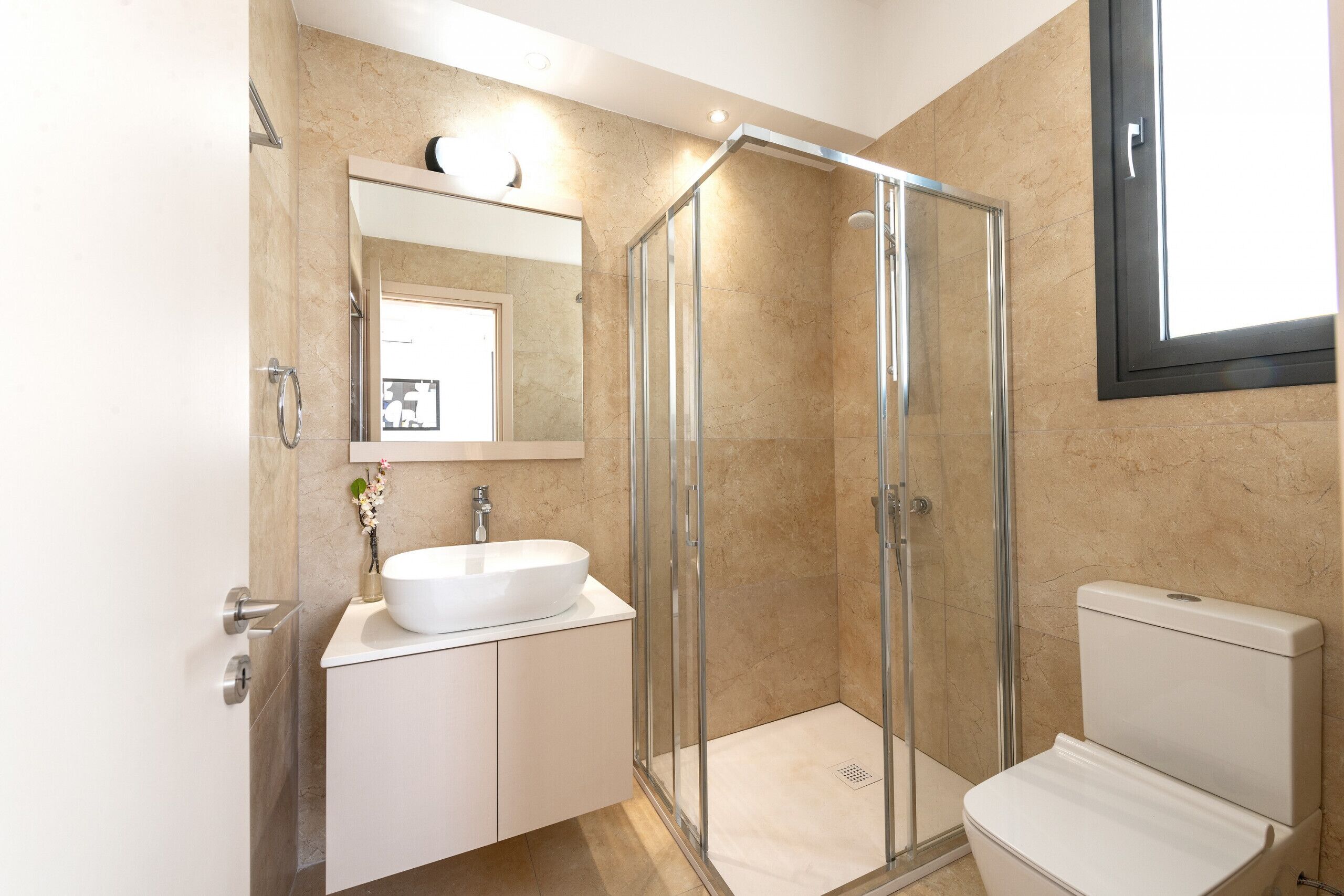 A modern bathroom with a glass-enclosed shower, a white sink, and a toilet.