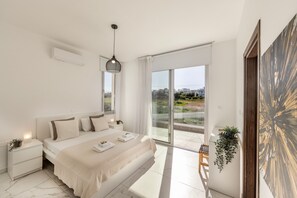 Une chambre à coucher moderne avec un grand lit, des tables de chevet, un luminaire suspendu, une porte-fenêtre coulissante donnant sur un balcon et une vue sur le paysage urbain.