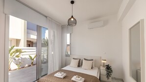 A modern bedroom with a large bed, a sliding glass door to a balcony, and a ceiling light fixture. - Protaras Sol e Mar Villa 2 (Paralimni)